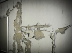 Example of asbestos-containing exterior paint on concrete substrate with significant damage.