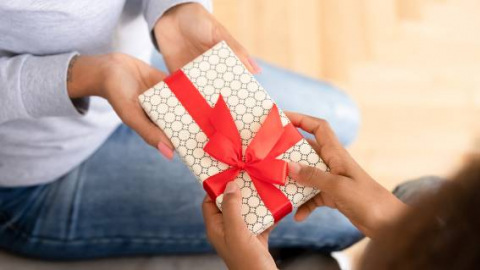 Hands holding gift with red ribbon