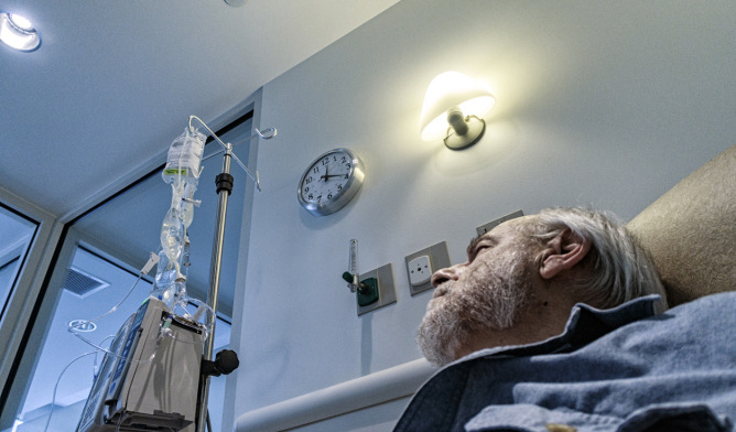 Senior male cancer patient looking at his IV bag.