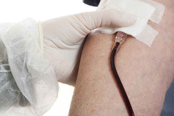 A nurse in protective uniform and wearing gloves taking blood sample from an elderly person. Close up.