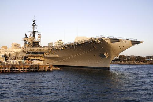 A navy ship docked at a navy shipyard.
